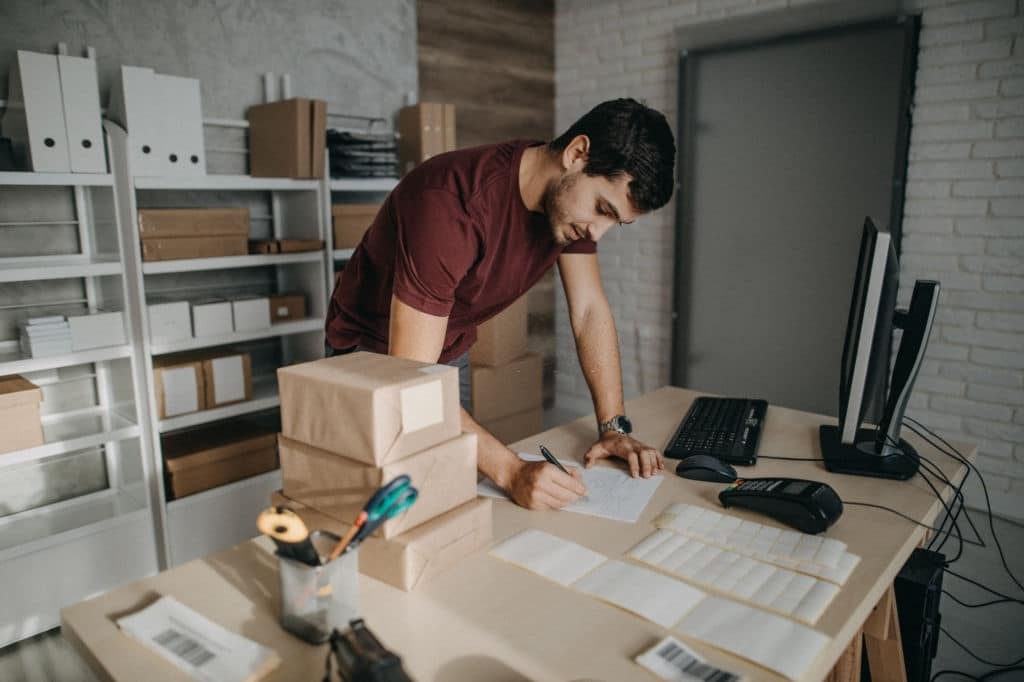 Delivery person preparing bar codes for packages, checking to do list